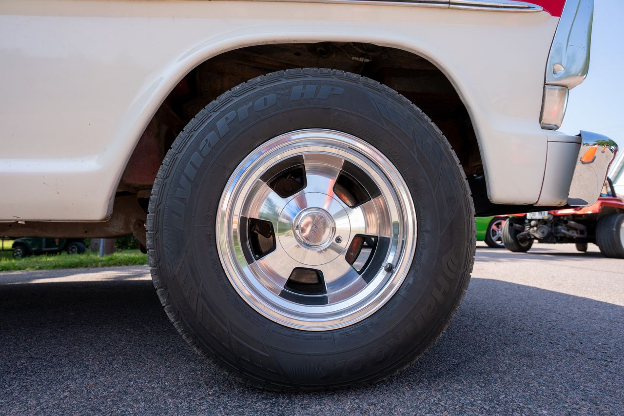 Detailed view of a classic car wheel with chrome rim and DynaPro tire on a sunny day.