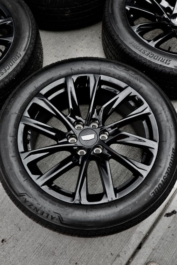 High-quality image of a new black alloy wheel and tire on concrete surface.