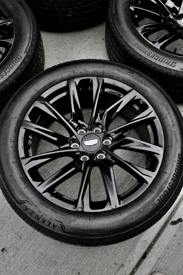 High-quality image of a new black alloy wheel and tire on concrete surface.