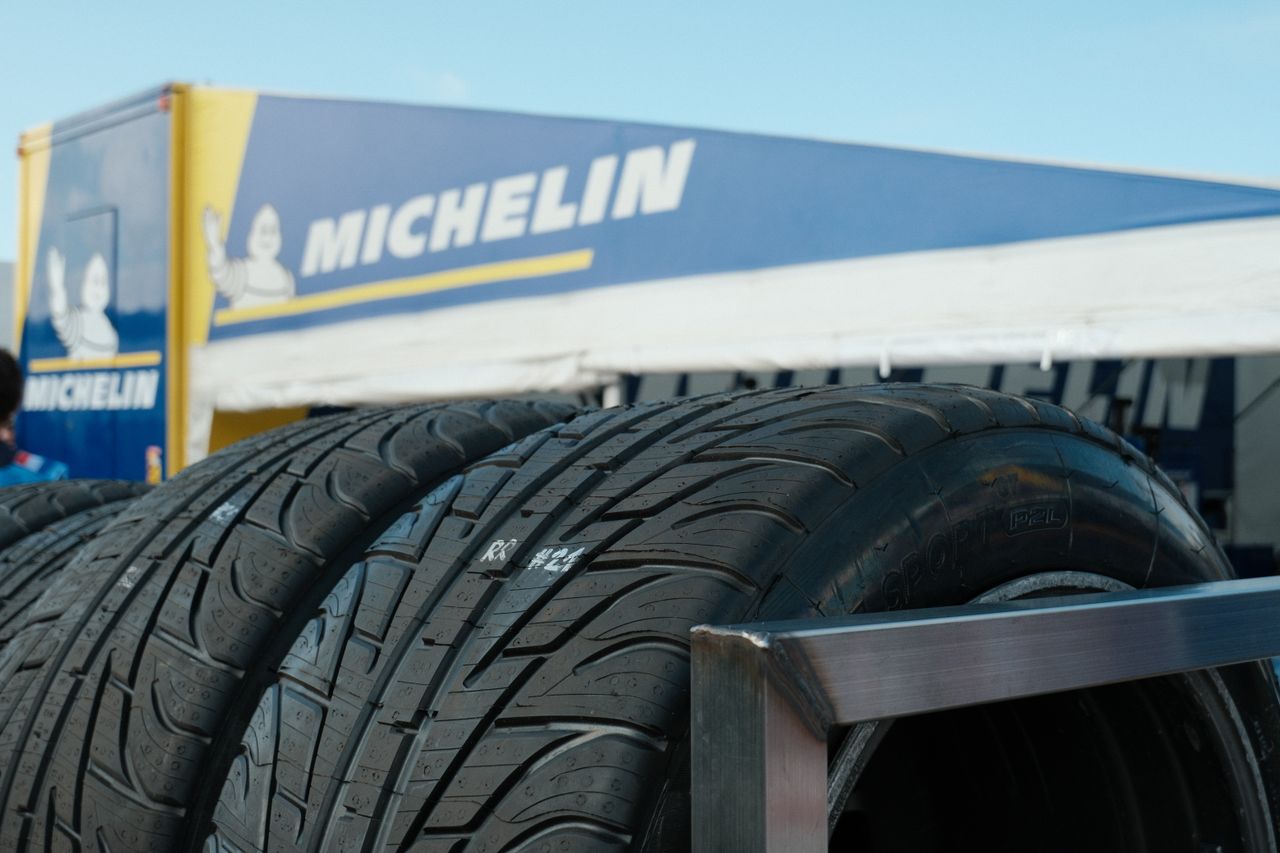 Stacked car tires displayed at an automotive event, featuring prominent branding.