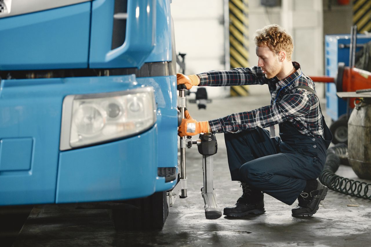 A male mechanic is aligning truck tires in a professional workshop setting.